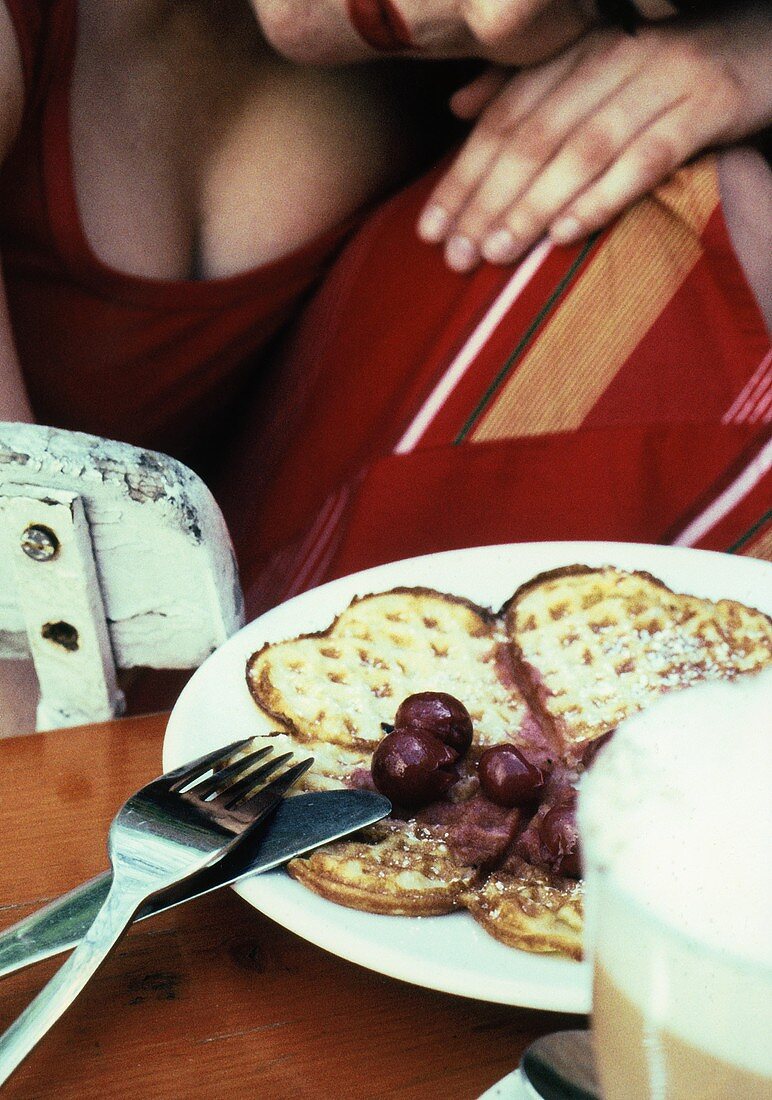 Waffles with cherry compote, woman in background