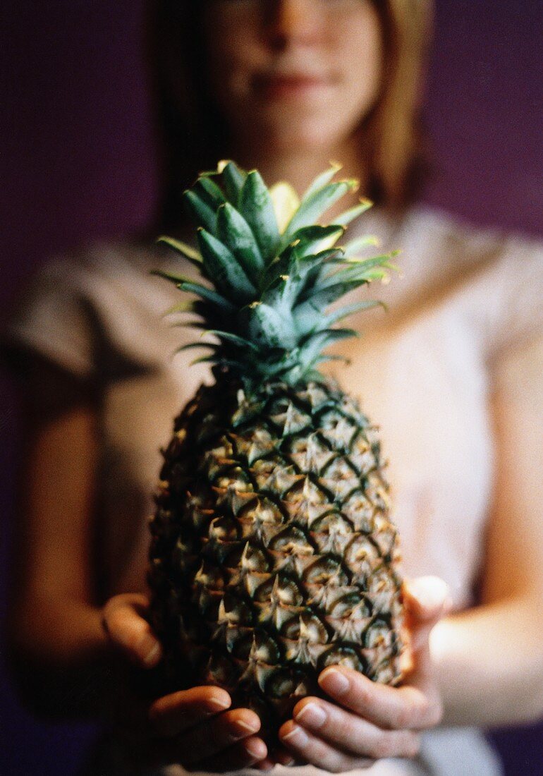 Fresh pineapple in a young woman's hands