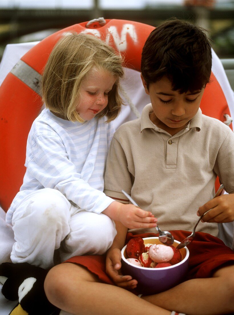 Two children eating ice cream from one bowl