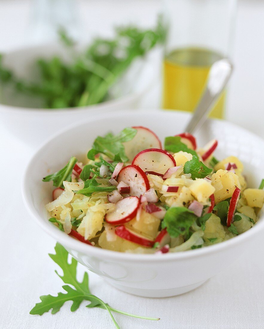 Hearty potato salad with white cabbage, radishes and rocket