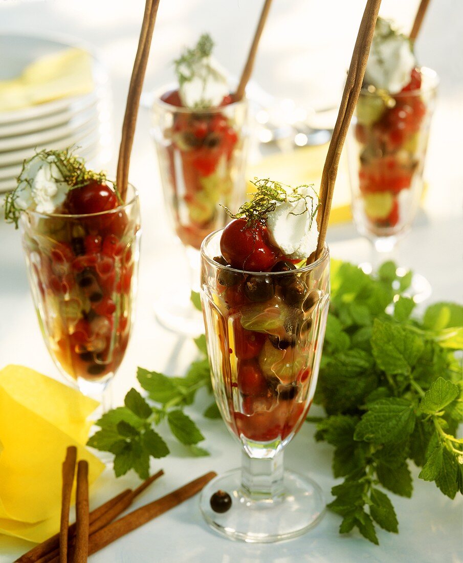 Berry salad with cherries, cream and mint in glasses