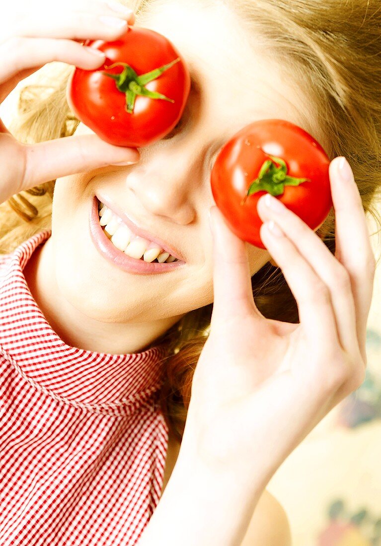 Girl with holding tomatoes in front of her eyes