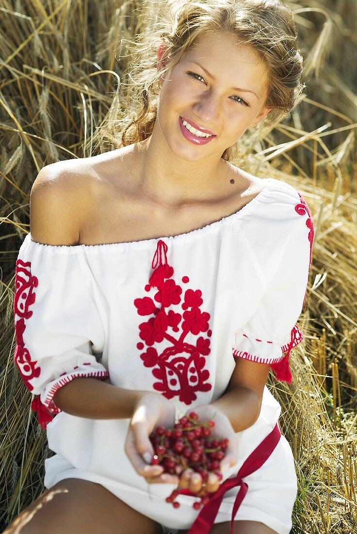 Young woman holding redcurrants in her hands