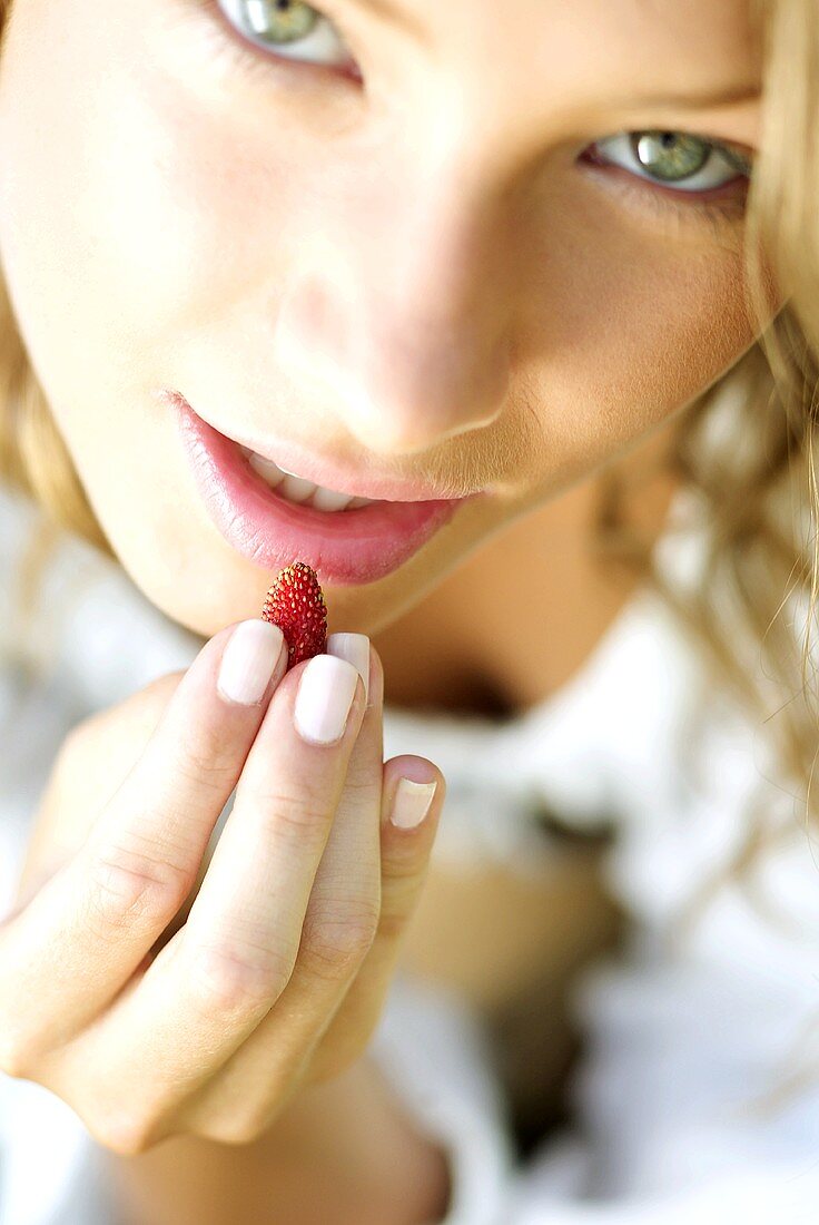 Young woman eating a wild strawberry
