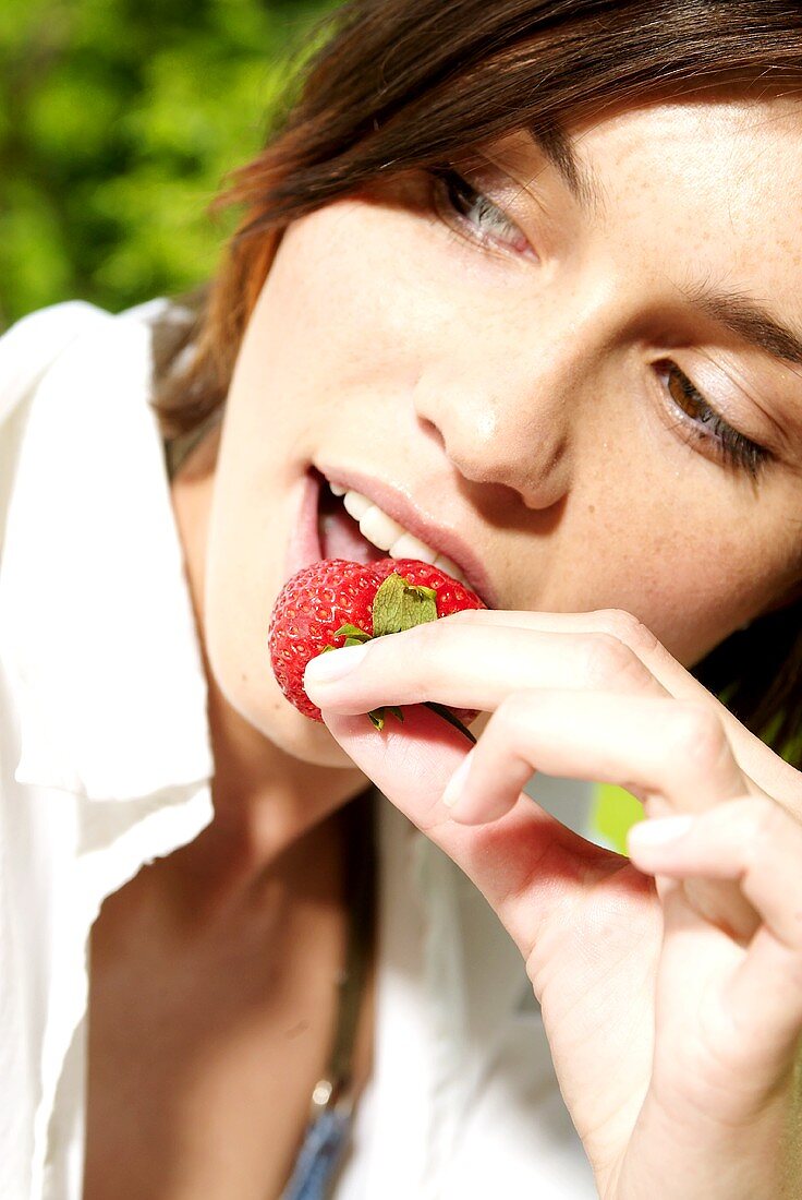 Frau beisst in eine Erdbeere