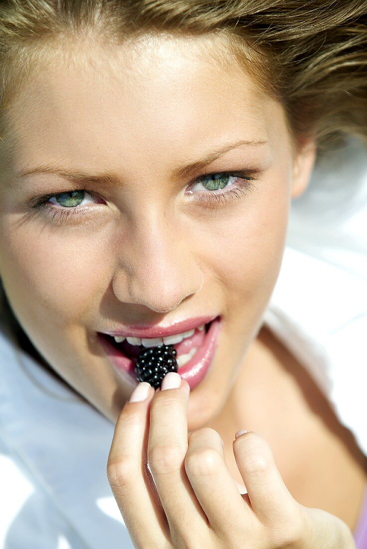 Young woman eating a blackberry