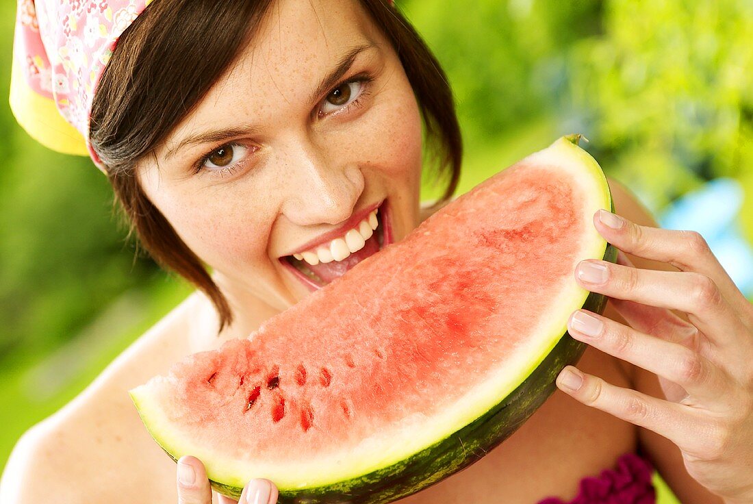 Frau hält beisst in ein Stück Melone