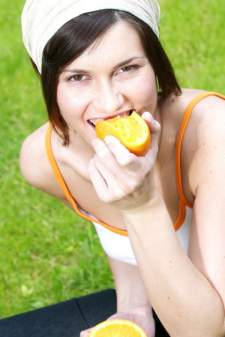 Frau beisst in eine Orangenhälfte