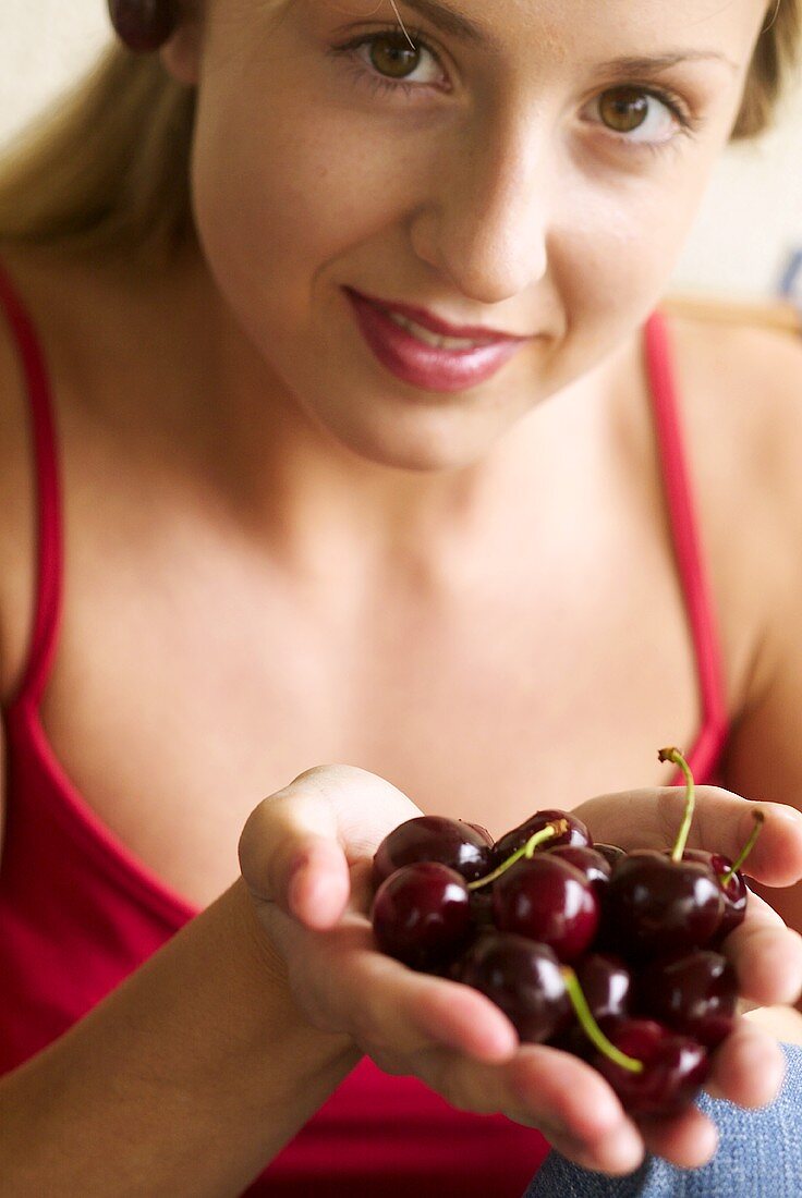 Young woman holding cherries in her hands