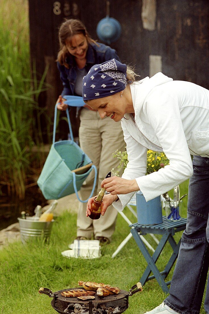 Zwei junge Frauen beim Grillen am See