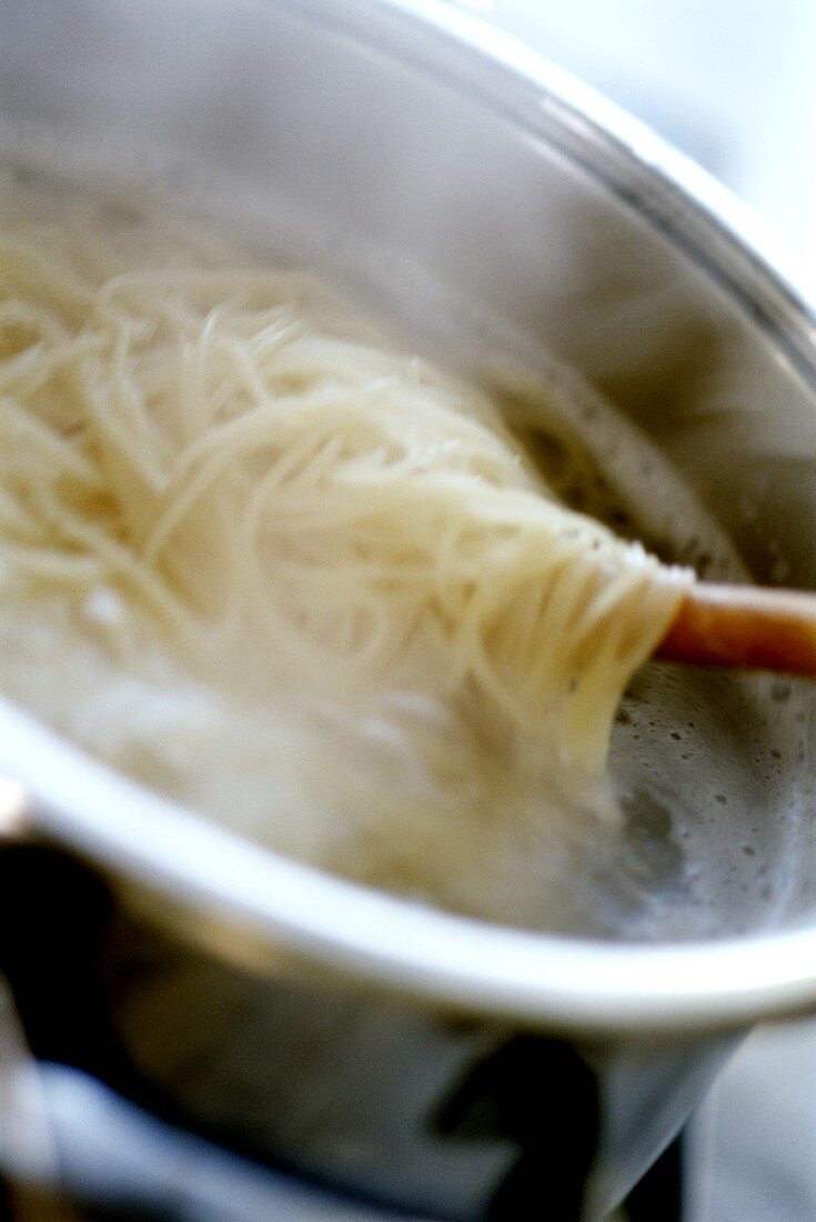 Spaghetti im Kochtopf mit Holzlöffel umrühren
