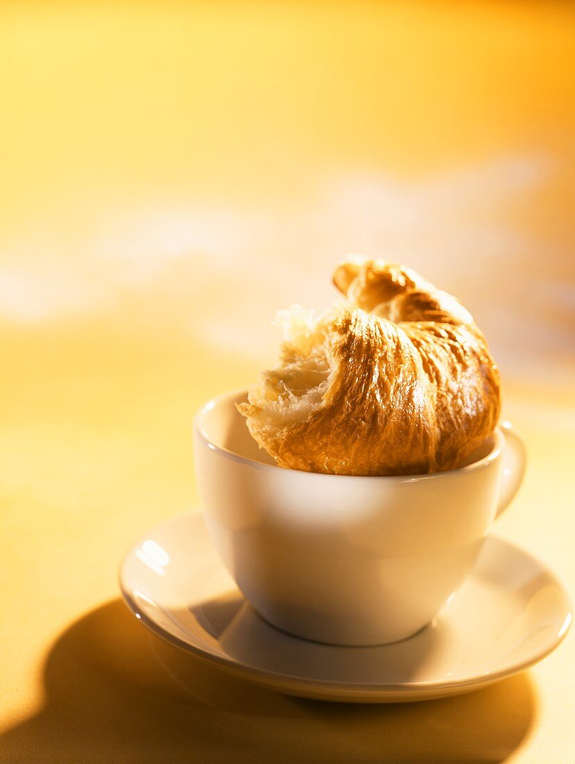 Angebissenes Croissant auf einer Kaffeetasse