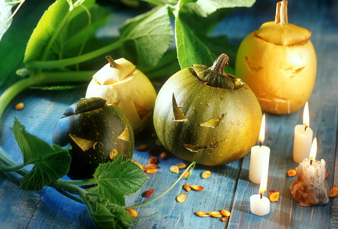 Halloweenkürbisse auf blauem Holztisch, daneben Kerzen