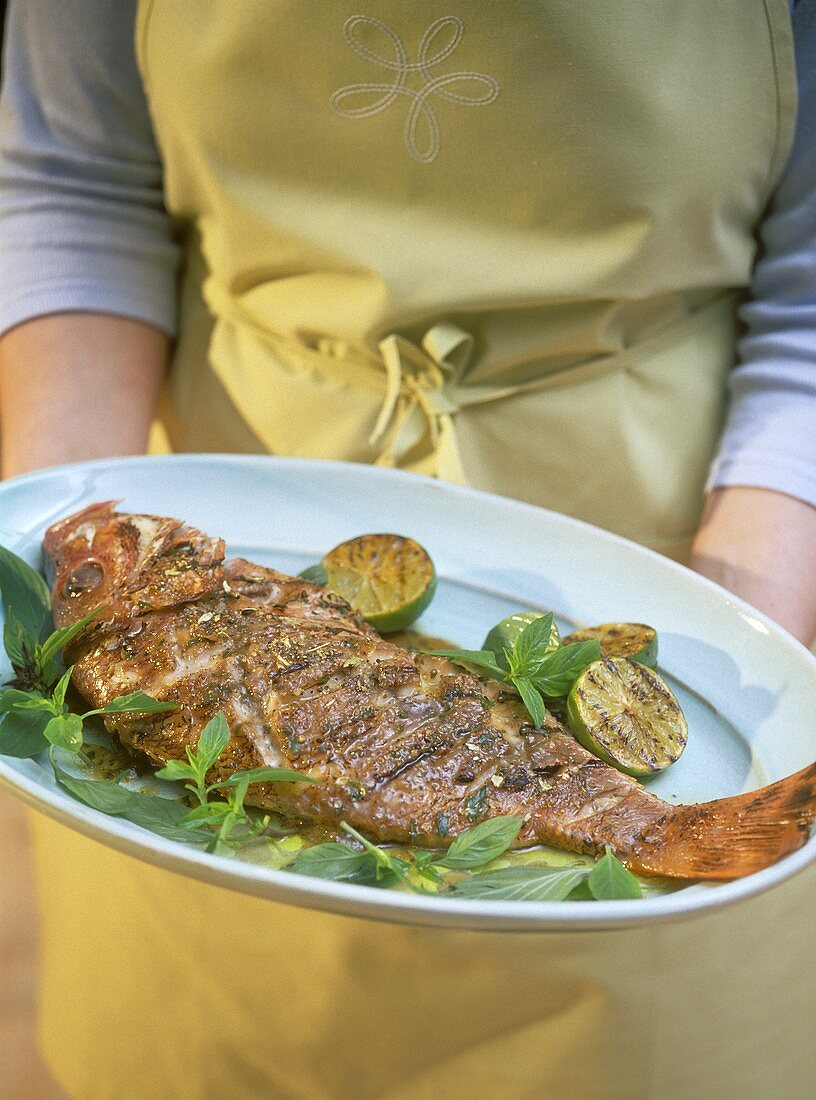 Woman holding platter of red snapper with tamarind puree