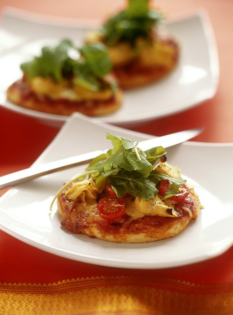 Mini-pizza with artichokes, tomatoes and rocket