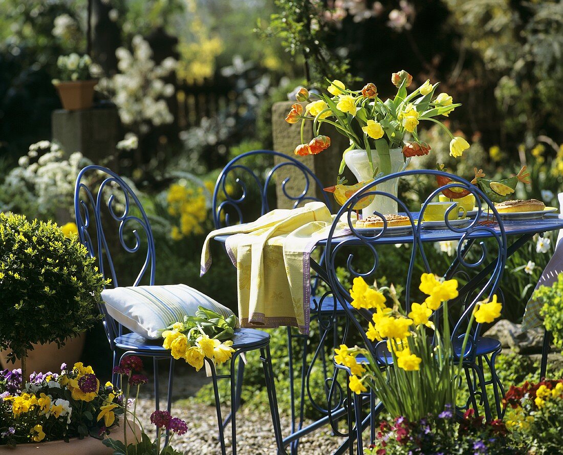 Table laid for coffee with spring flowers in garden