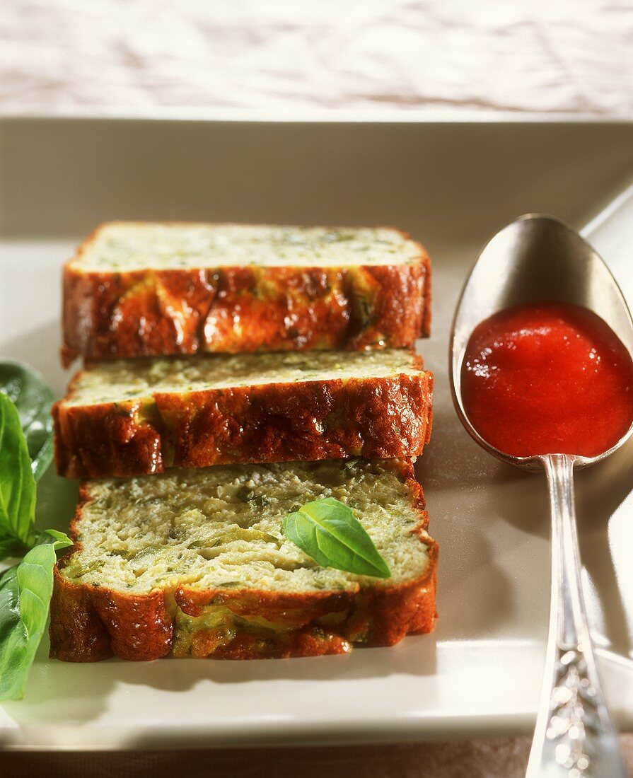 Zucchini-Flan in Scheiben, Basilikum und Löffel Tomatensauce
