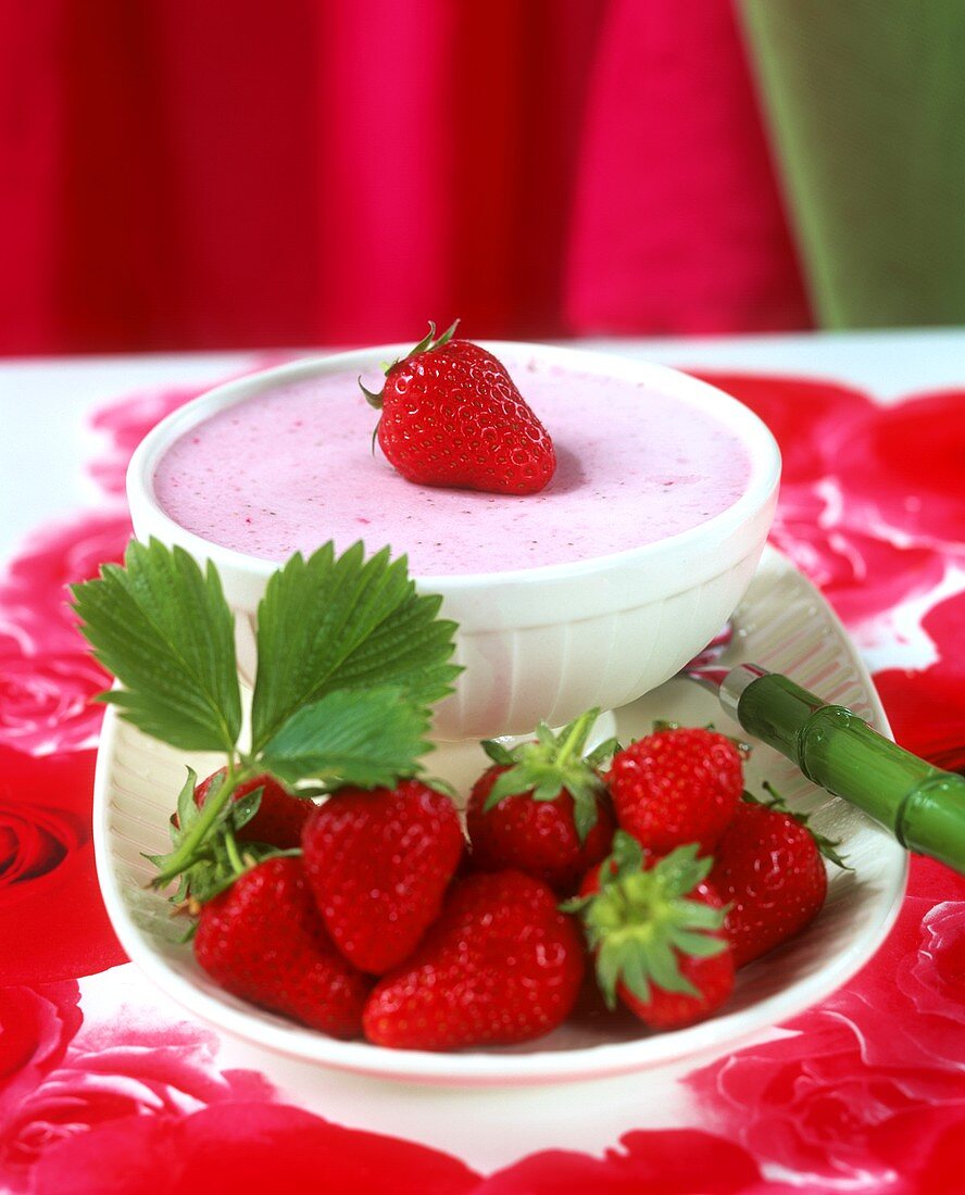 A bowl of strawberry cream and fresh strawberries