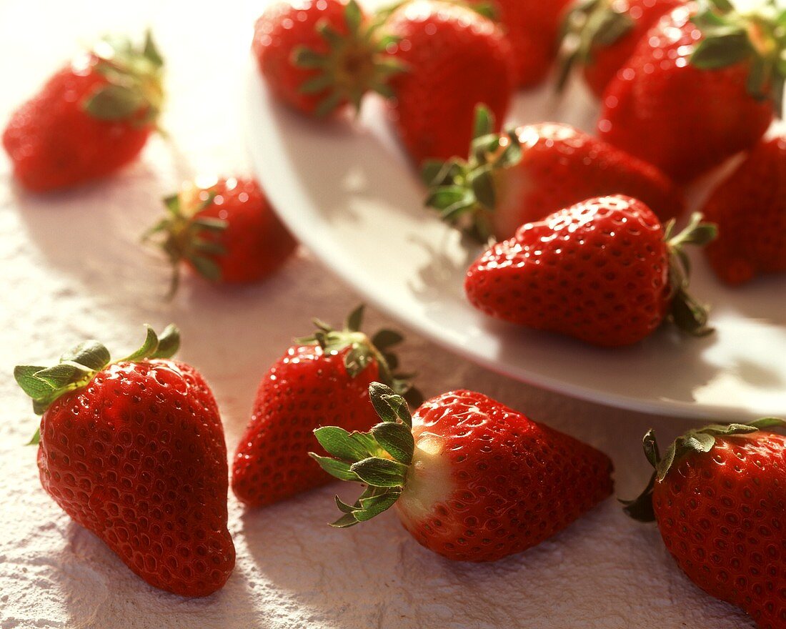 Strawberries on and beside a white plate