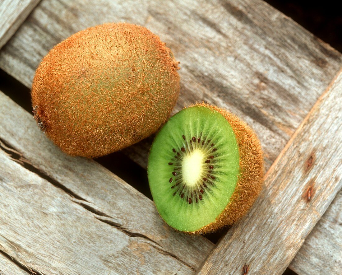 Kiwi fruits, whole and cut open, leaf in background