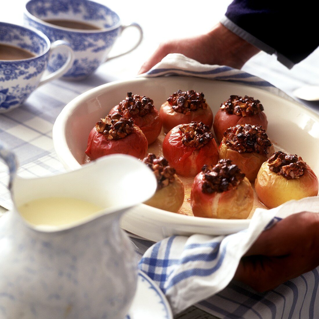 Hands serving baked apples with custard