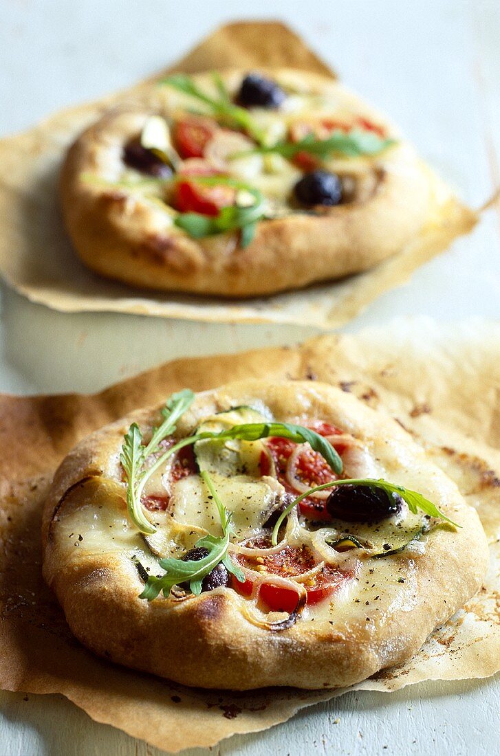 Pizzette (Zwei Minipizzen mit Gemüse, Rucola und Käse)