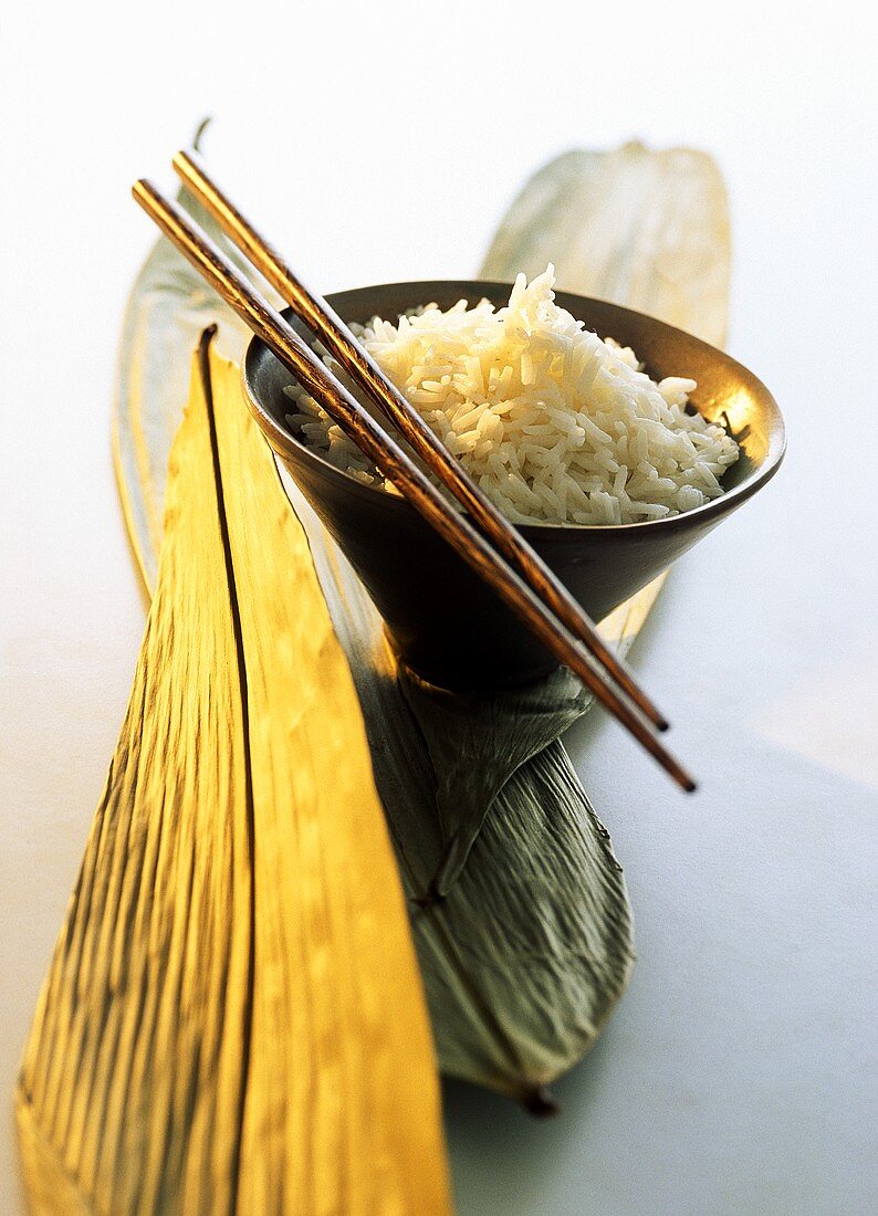 Gekochter Reis in einer Holzschale; Stäbchen