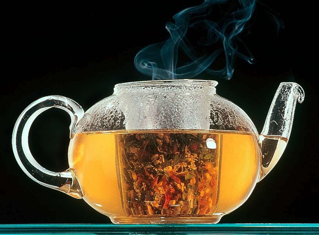 Steaming herb tea in glass teapot