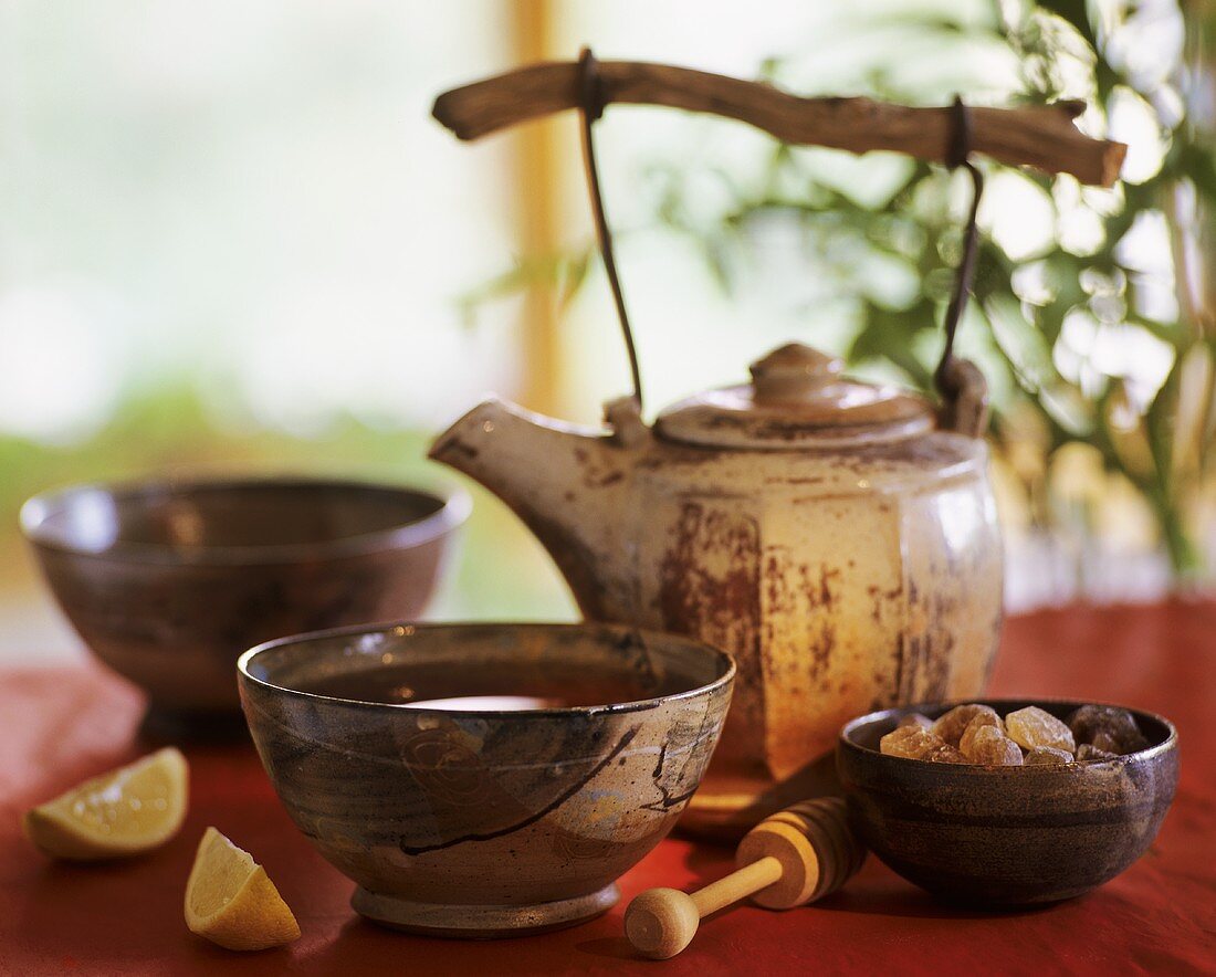 Asian teapot, two bowls of tea and sugar crystals