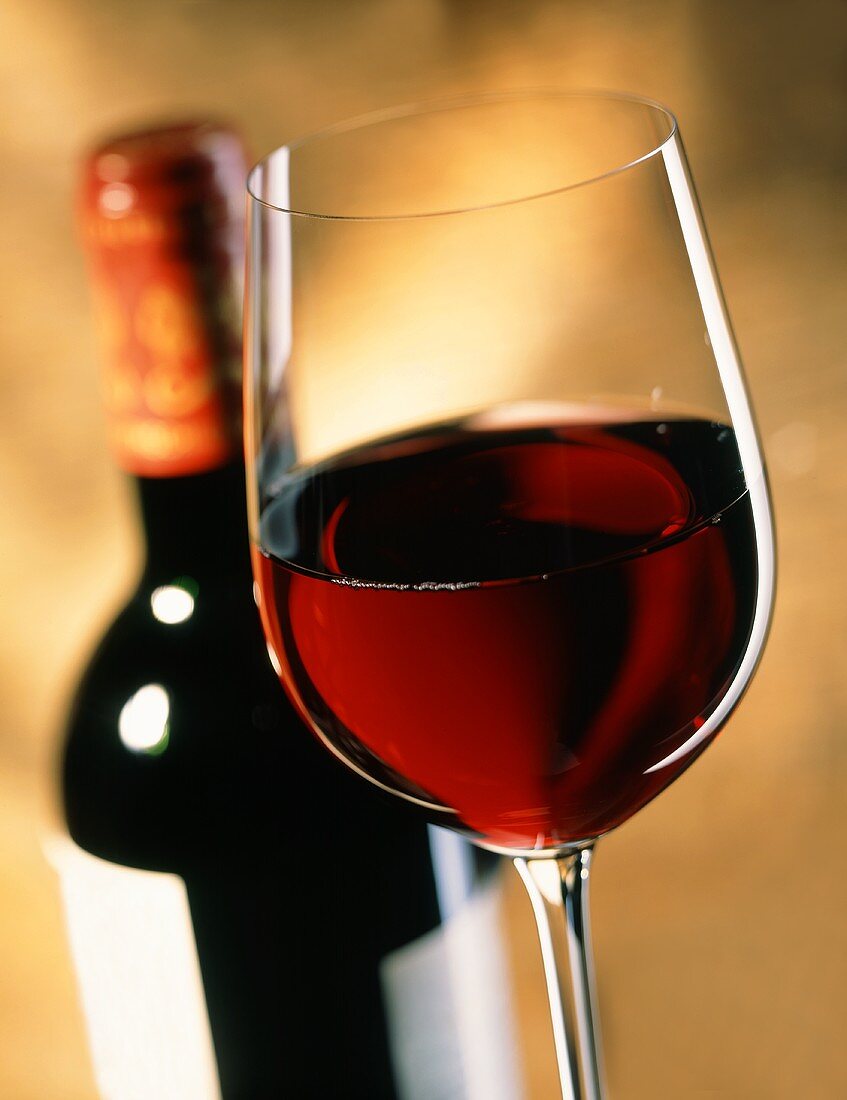 Glas Rotwein vor Flasche