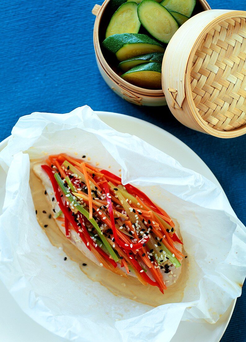 Chicken breast, strips of vegetables & sesame on baking paper