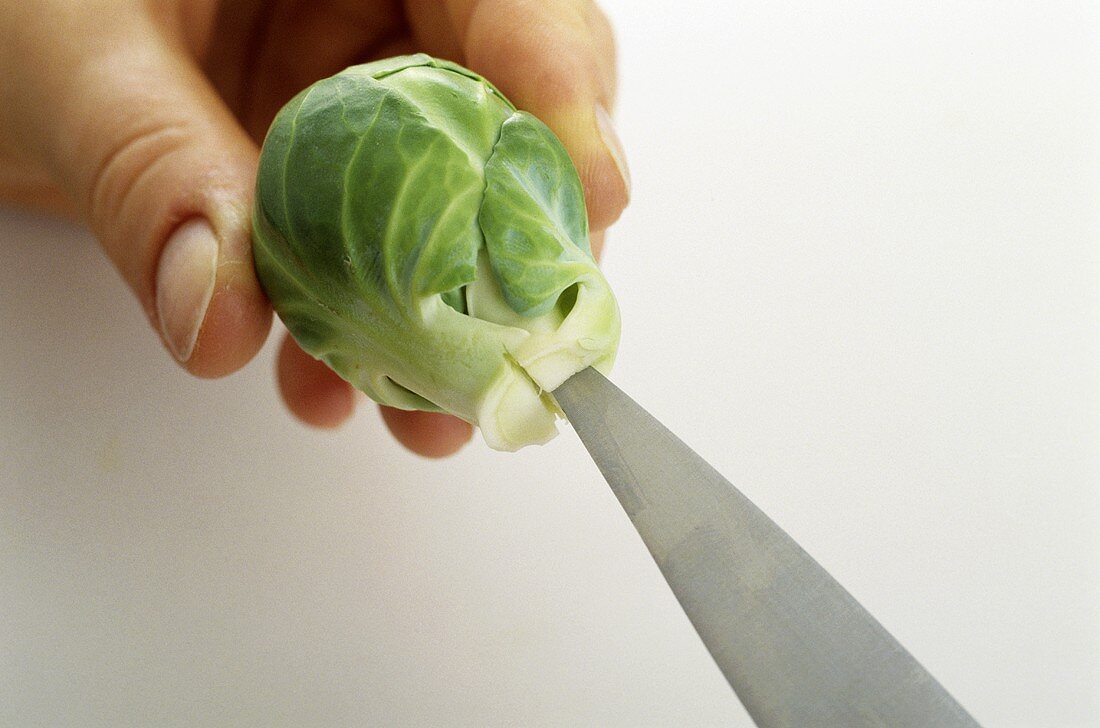 Making a crosswise cut in the base of Brussels sprouts