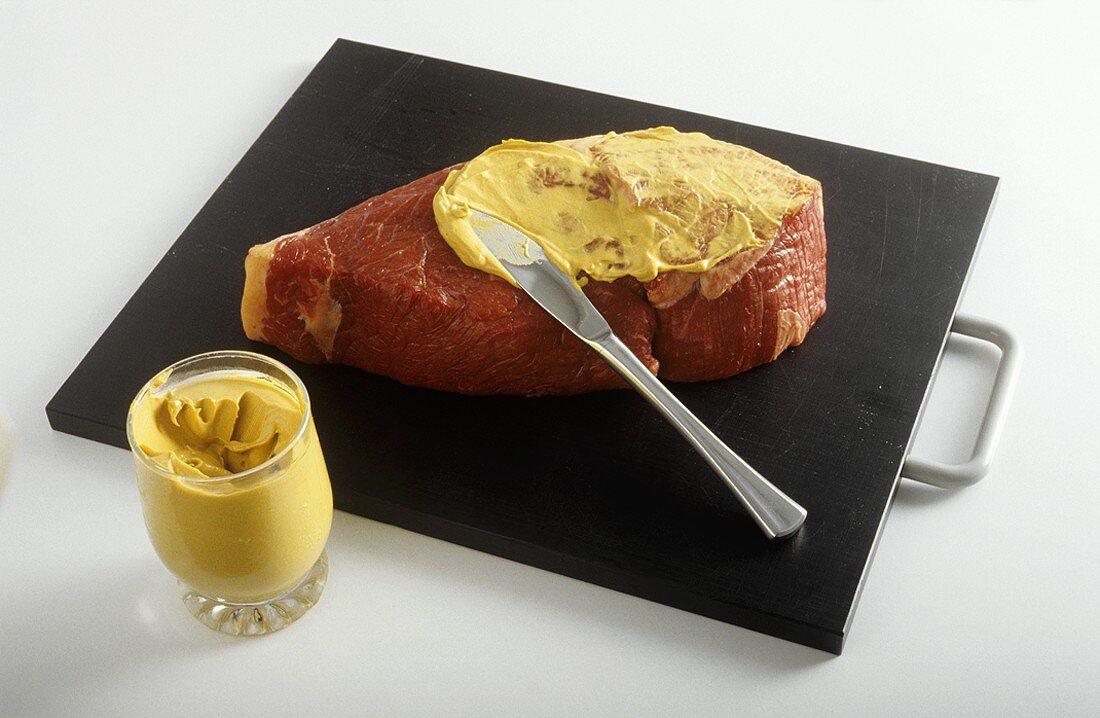 Spreading mustard on steak