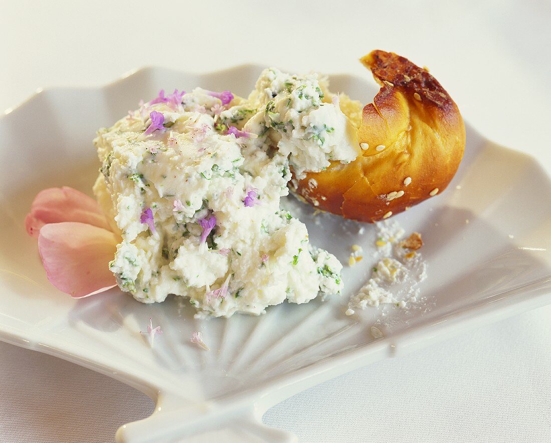 Kräuterquark mit Essblüten und ein Stück Brötchen