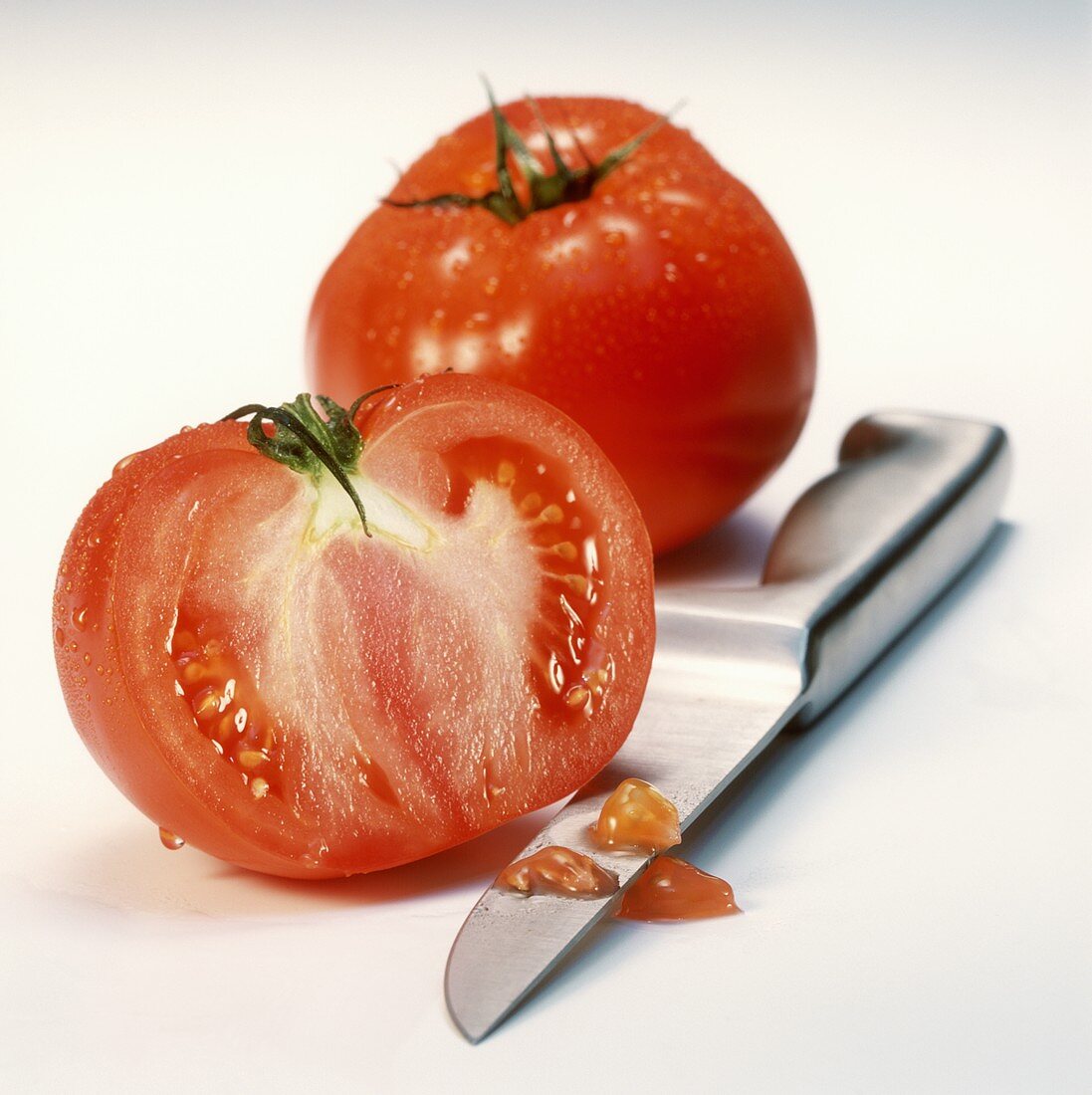 Half and whole beefsteak tomato with knife