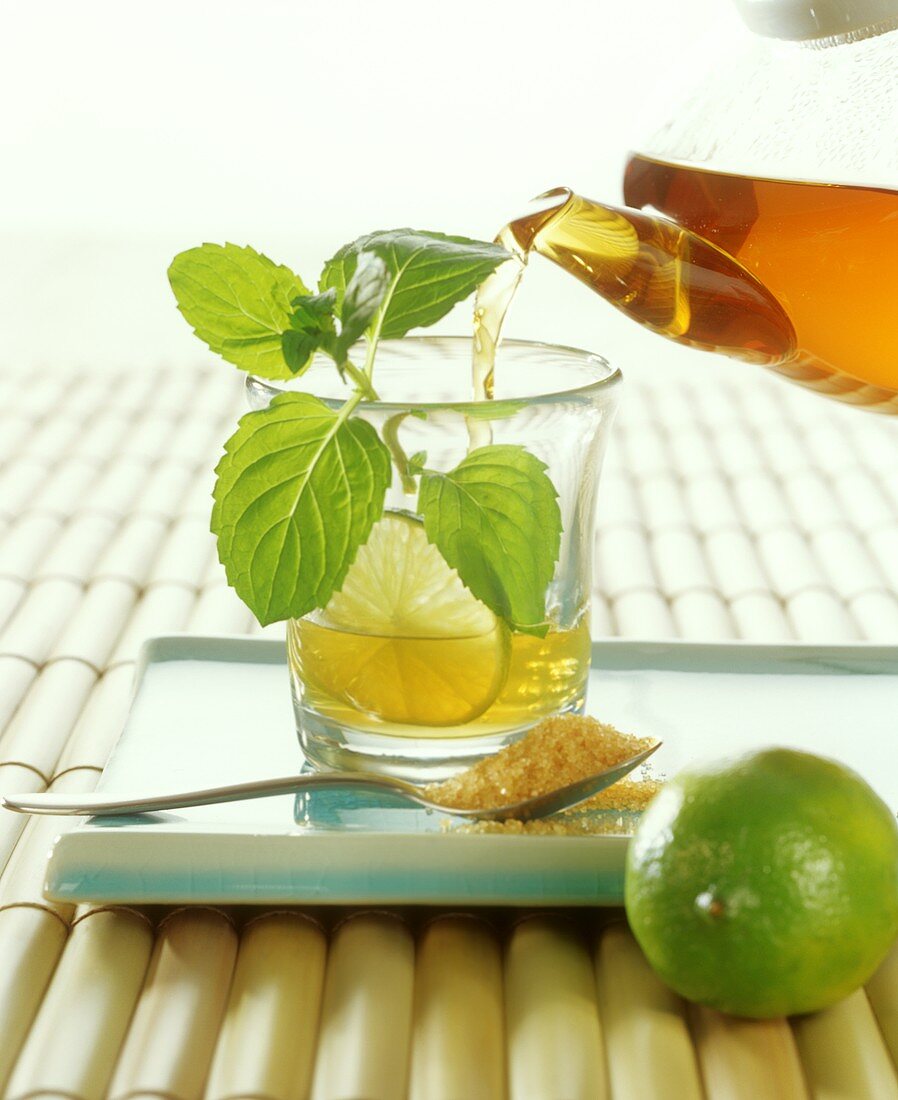 Pouring lime and mint tea into glass