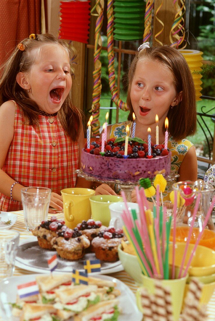 Two girls blowing out candles on birthday cake