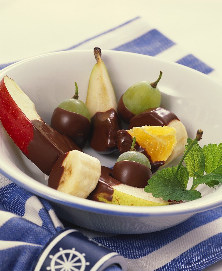 Assorted chocolate-coated fruits in a bowl