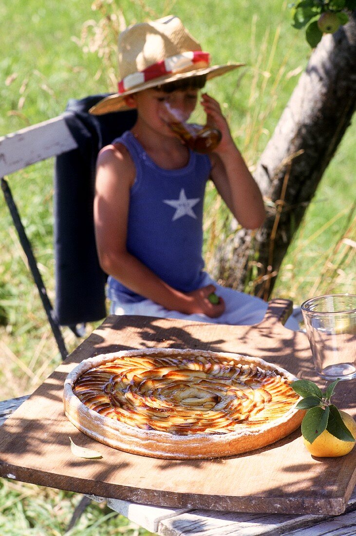 Small boy with apple tart and apple juice in open air