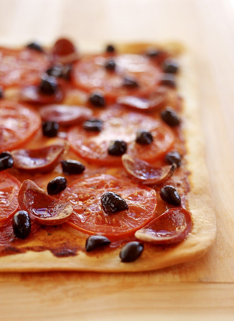 Pizza mit Wurst, Tomaten und Oliven