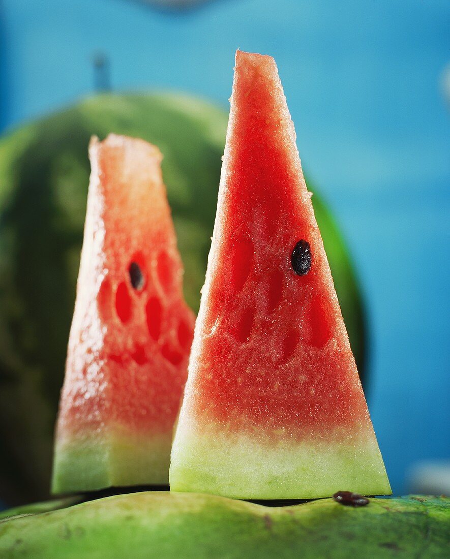 Zwei Stück Wassermelone vor ganzer Melone