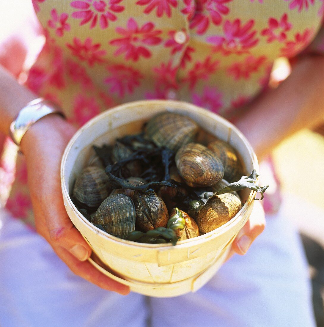 Woman holding wood-chip bowl of fresh mussels