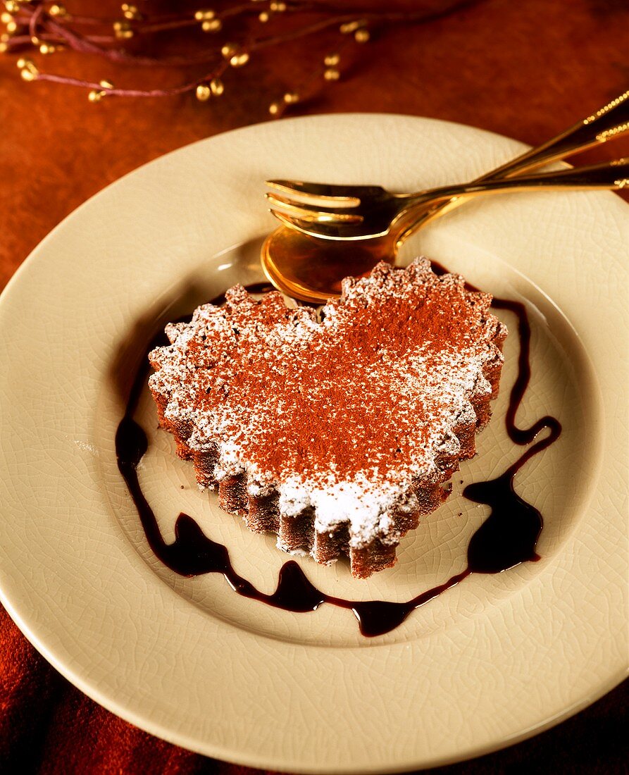 Herzförmiger Schokoladenkuchen mit Schokosauce auf Teller