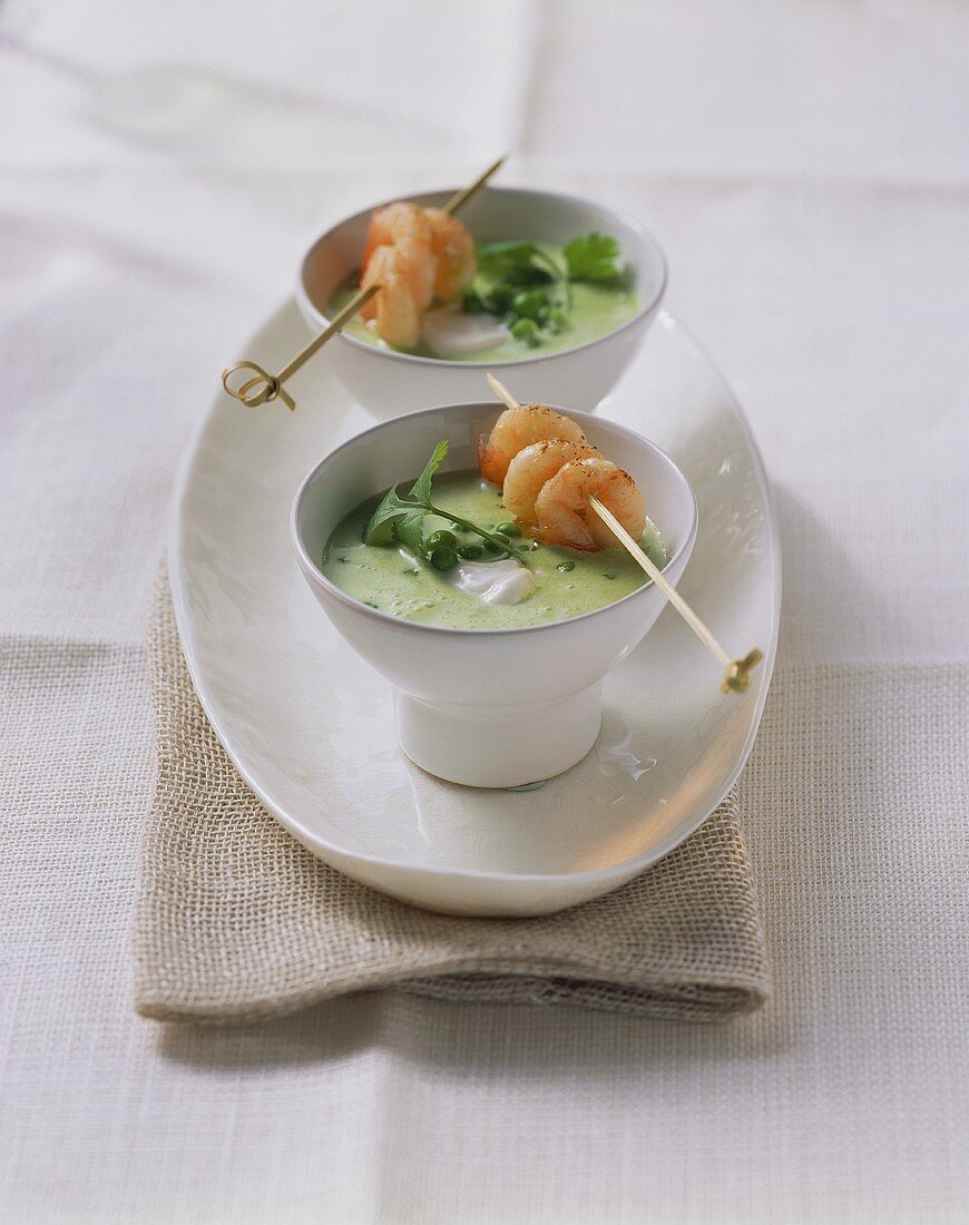 Two bowls of pea soup and shrimp kebab
