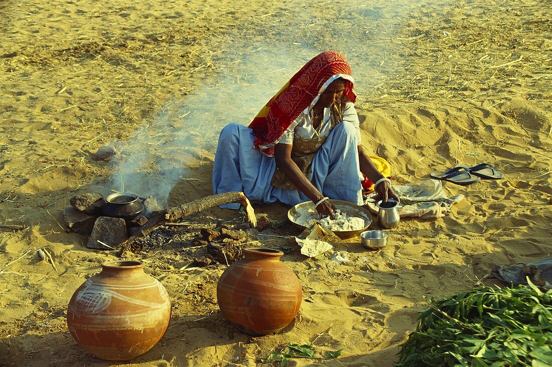 Frau am Boden sitzend beim Essen kochen (Rajasthan, Indien)