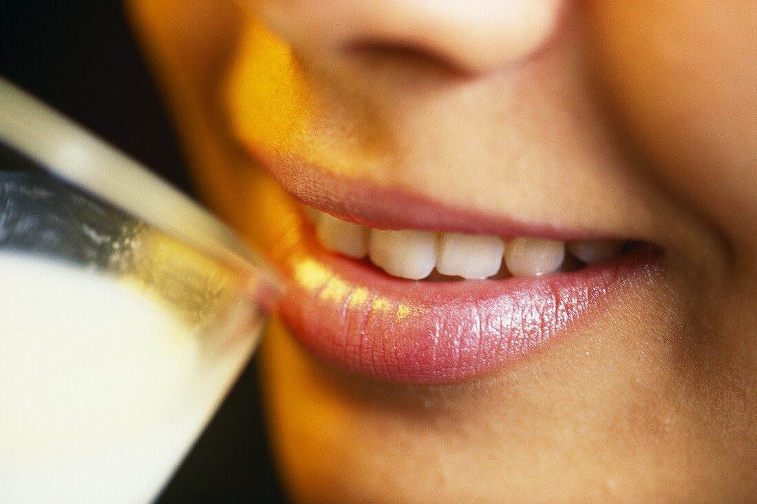 Woman putting glass of milk to her lips (detail)
