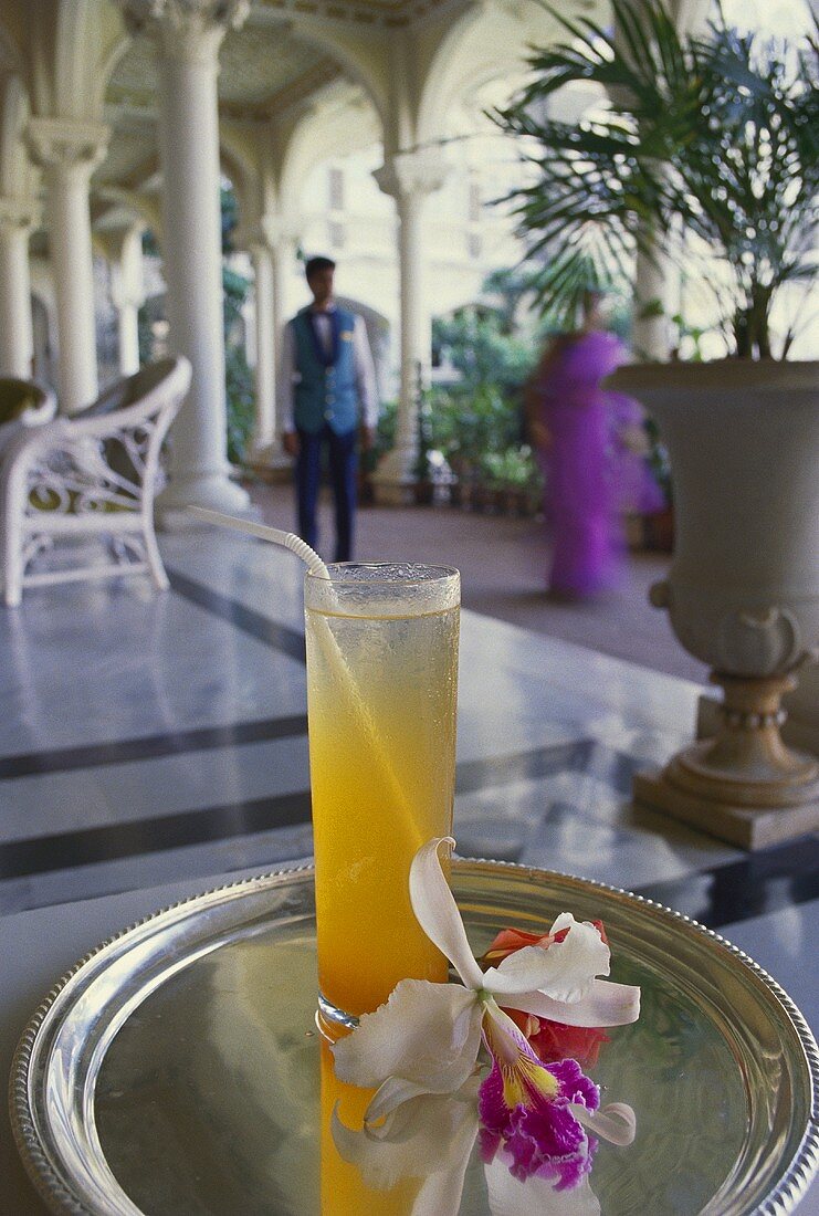 Long drink on a silver tray with an orchid