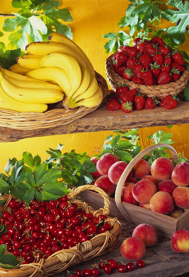 Körbe mit Bananen, Erdbeeren, Kirschen und Pfirsichen