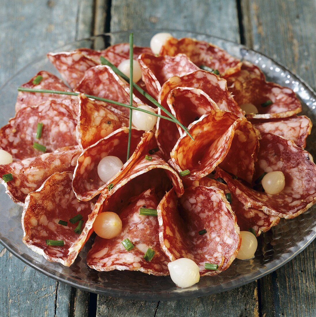 Sliced salami served with pearl onions