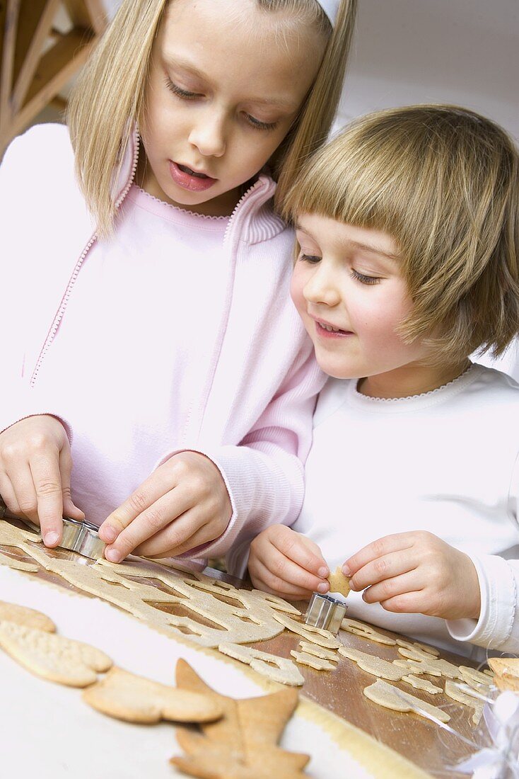 Two girls cutting out Christmas biscuits